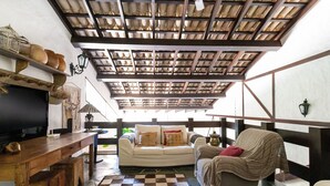 A cozy living area with a checkered rug, a sofa, a chair, a wooden table, and a television. - Sítio Dels Serrans - Jacareí (Jacarei)