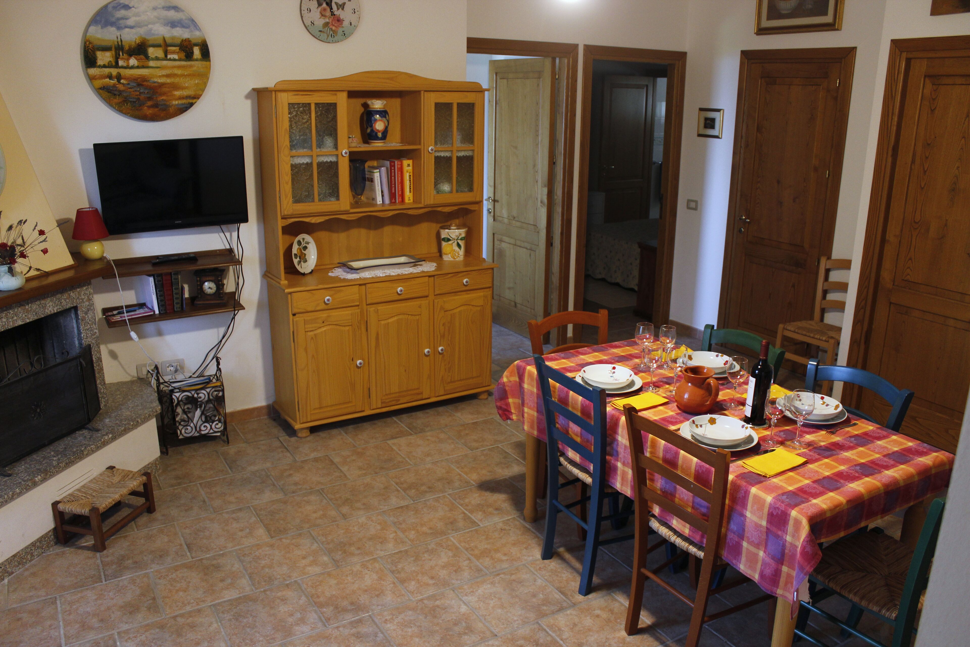 Un coin repas avec une table dressée pour quatre personnes, un buffet en bois, un téléviseur et une cheminée.