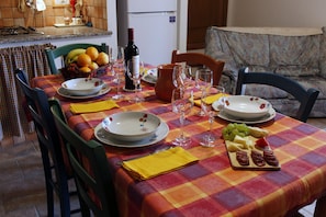 Taula de menjador preparada amb plats, gots, una ampolla de vi i un plat de fruita.