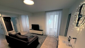 A modern living room with a sofa, TV, and a dining area. - San Carlo Apartments (Lugano)