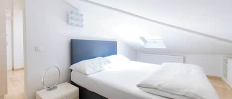 Ein modernes Schlafzimmer mit Bett, Nachttisch und Dachfenster.
