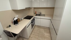 A compact kitchen with white cabinets, a black countertop, and a sink. - San Carlo Apartments (Lugano)