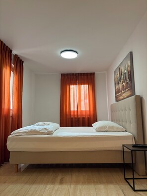 A bedroom with a bed, curtains, a painting, and a ceiling light. - San Carlo Apartments (Lugano)