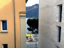 A narrow street with buildings on either side, a clear view of a lake, and a mountain in the background.