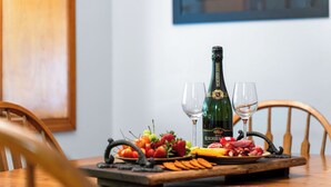 Ett träbord med en flaska Roederer Brut-champagne, två glas och en bricka med charkuterier, frukt och kött.