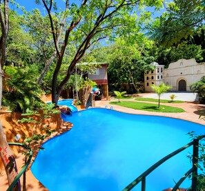 A swimming pool surrounded by lush greenery and a historic building.