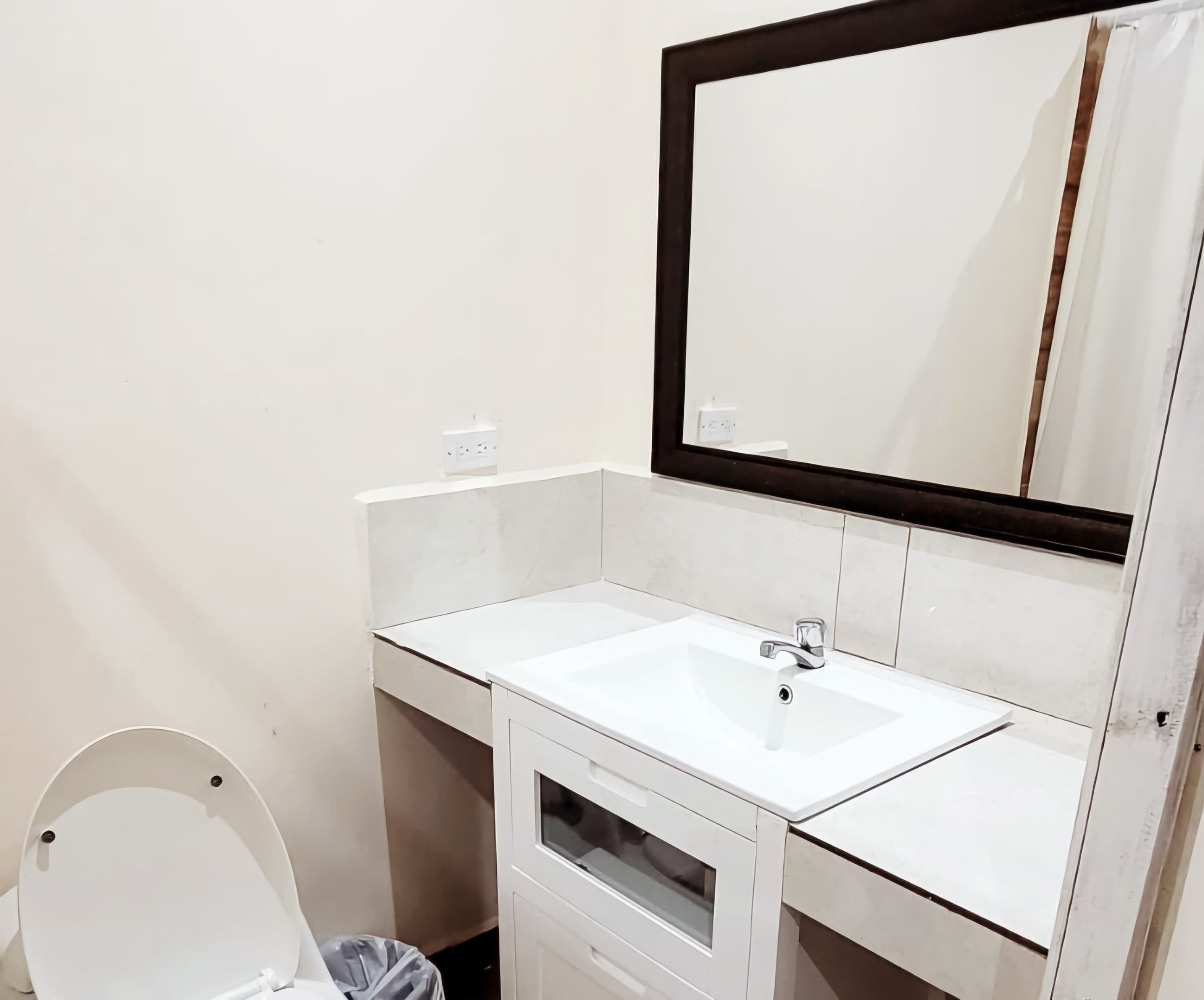 Un baño pequeño y limpio con un lavamanos blanco, un espejo y un inodoro.