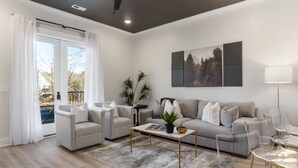 A modern living room with a grey sofa, two armchairs, a coffee table, and a glass dining table. - 3 Bedroom, Main Level (Helena)
