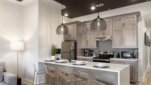 A modern kitchen with a central island, bar stools, and stainless steel appliances. - 3 Bedroom, Main Level (Helena)