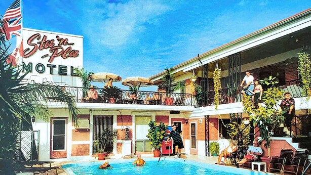 Un motel doté d’une piscine, d’un espace extérieur aménagé et d’un balcon avec des parasols.