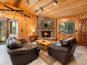 Ein gemütliches Wohnzimmer mit Ledersofas, einem Kamin und Holzwänden.