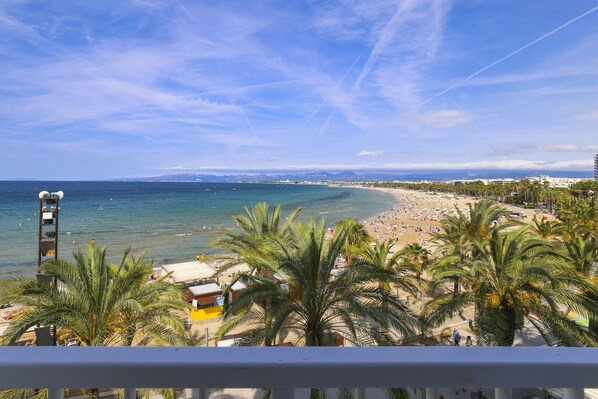 A beach view with palm trees, a lifeguard tower, and a clear sky.