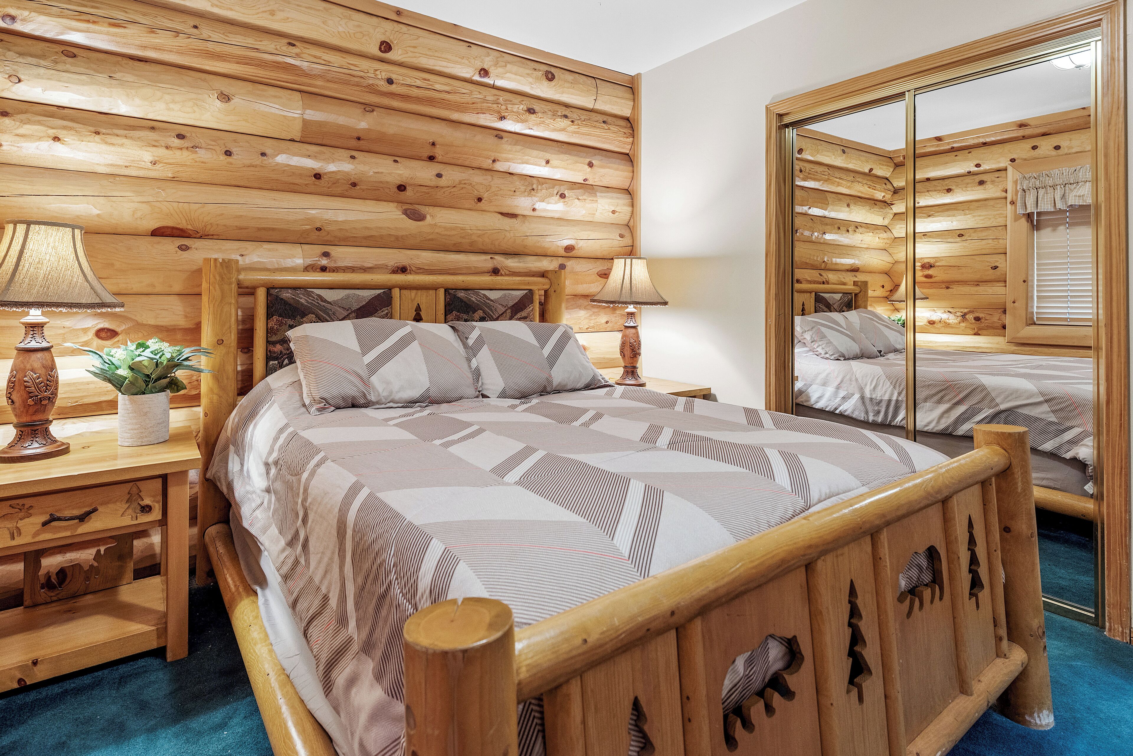 Une chambre aux murs lambrissés, avec un grand lit, deux tables de chevet dotées de lampes et un miroir.