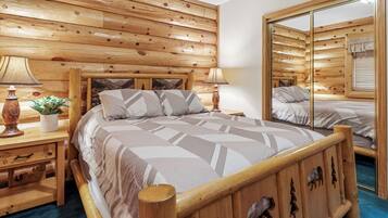 Une chambre aux murs lambrissés, avec un grand lit, deux tables de chevet dotées de lampes et un miroir.