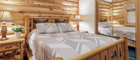 Un dormitorio con paneles de madera, una cama grande, dos mesitas de noche con lámparas y un espejo.