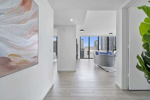 A modern interior with a hallway leading to a living area with a city view.