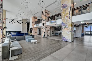 A spacious lobby with a modern design, featuring a seating area, a staircase, and a mezzanine level.