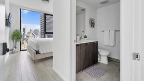 Ein modernes Schlafzimmer mit Stadtblick, ein separates Badezimmer mit Toilette, Waschbecken und Handtuchhalter.