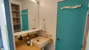 Un baño pequeño con lavamanos, espejo y lavadora.