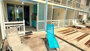 Un hotel con terraza de madera, dos sillones de descanso y balcón con barandillas.