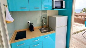 Una cocina compacta con armarios turquesa, un microondas, un lavamanos y un refrigerador.