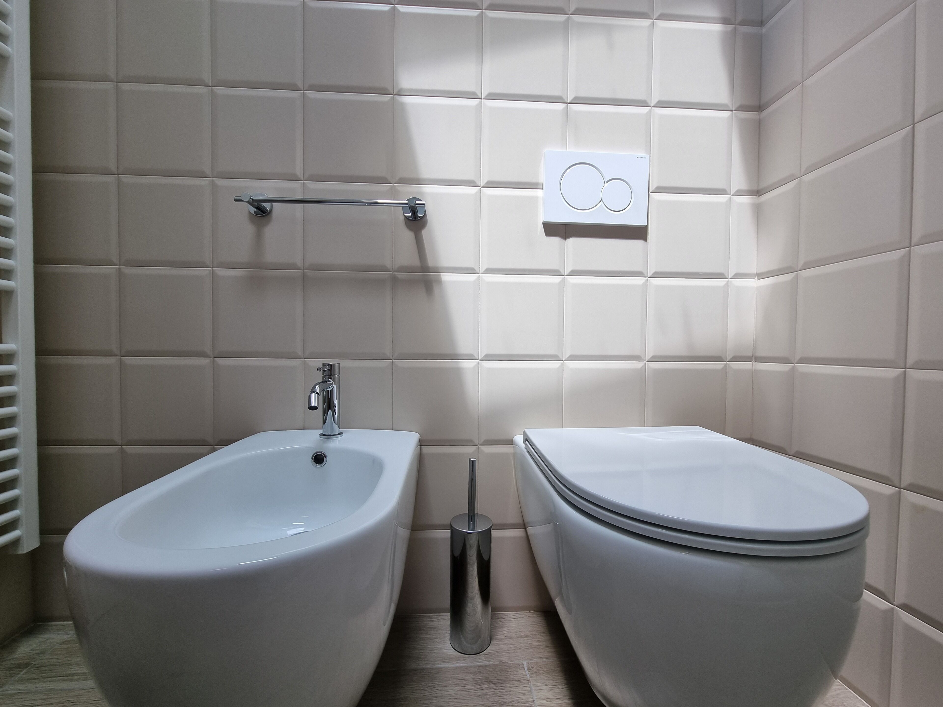 Une salle de bain équipée d’un bidet, de toilettes et d’un porte-serviettes.