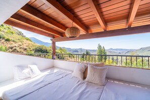 Un balcón con una cama, una lámpara colgante y vistas a las montañas.