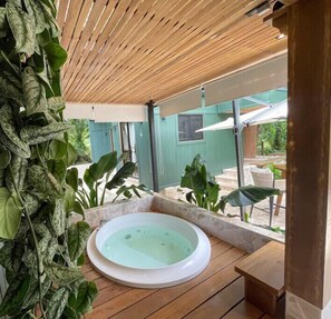 Tinaco en un área exterior cubierta con piso de madera y plantas verdes.