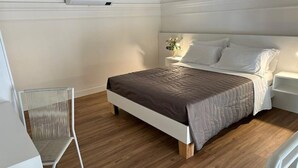 A neatly arranged bedroom with a bed, a chair, and a bedside table. - Executive suite (Catania)