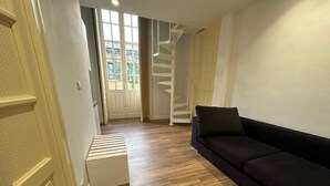 A room with a wooden floor, a dark-colored sofa, and a staircase leading to an upper level. - Executive suite (Catania)