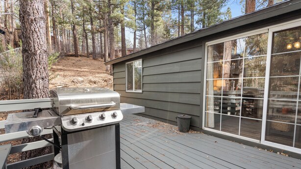 A barbecue grill on a wooden deck with a house in the background. - Dark Pine Retreat (Big Bear City)