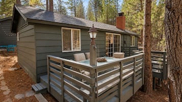 A cabin with a deck, a table, and chairs.