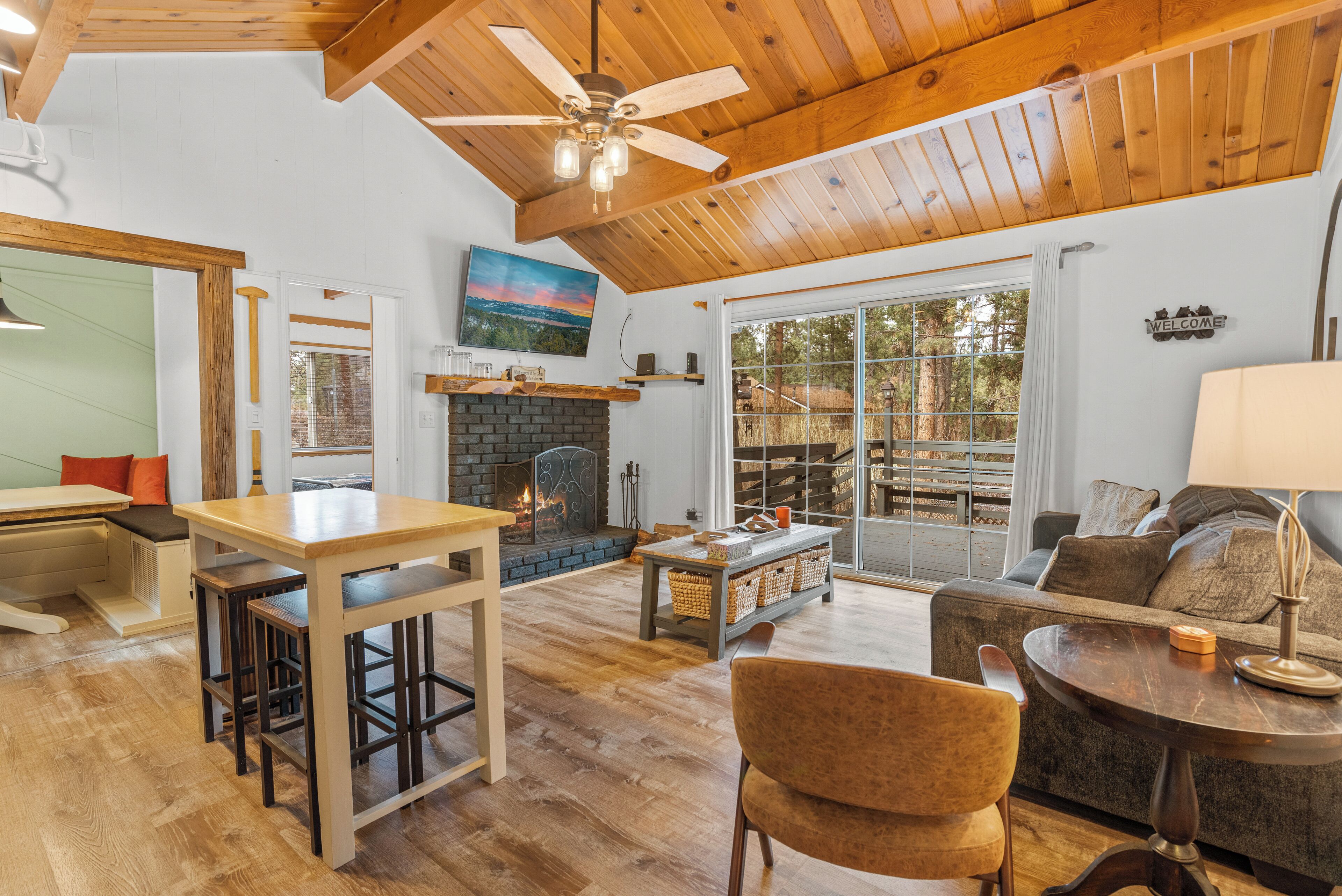 A spacious living area with a fireplace, wooden flooring, and a ceiling fan.