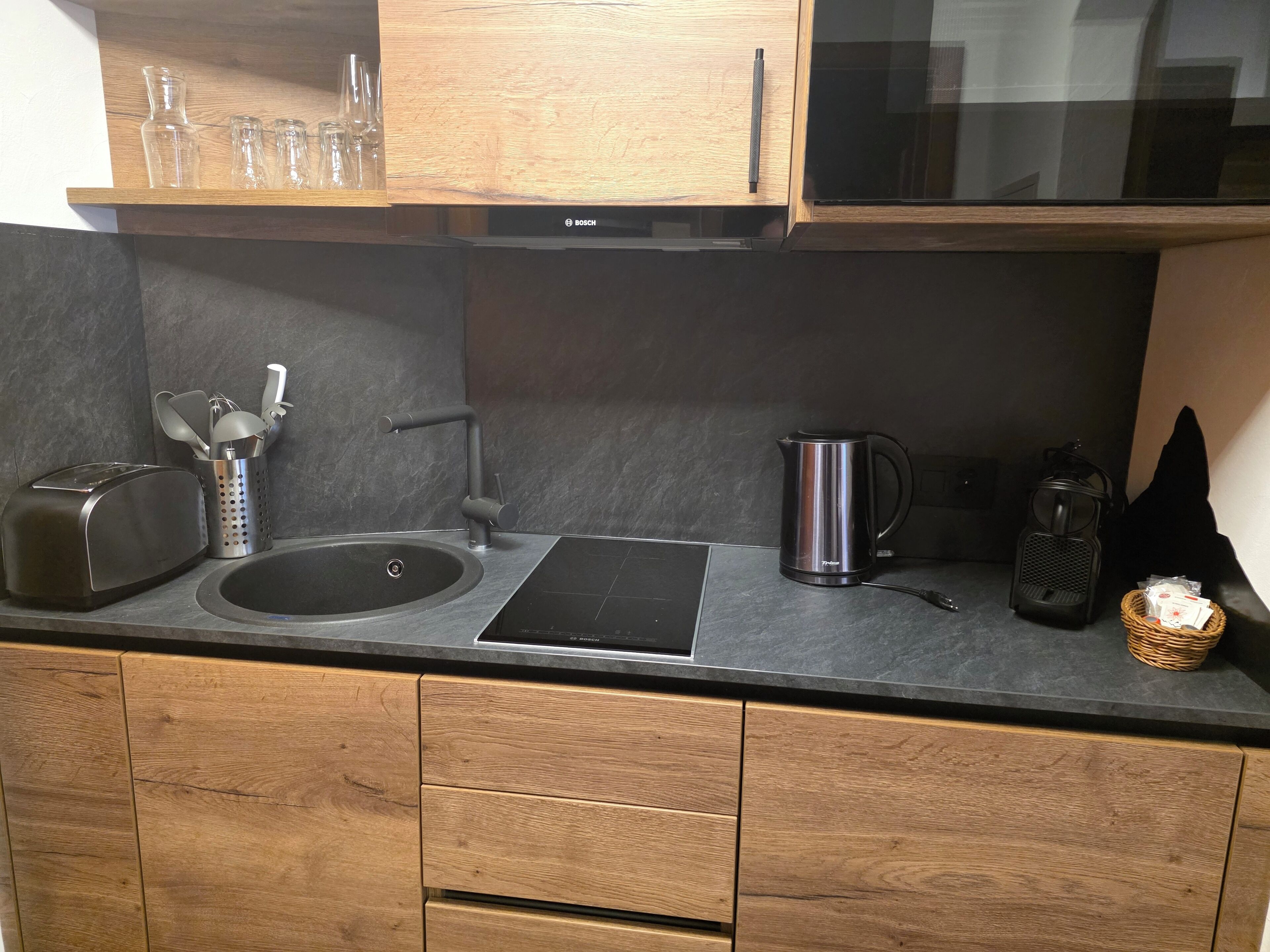 Una cocina moderna con armarios de madera, un lavamanos de acero inoxidable, un tostador, un hervidor y un microondas.
