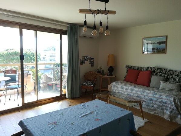 Een kamer met een bed, een tafel, een stoel, een lamp en uitzicht op het buiten.
