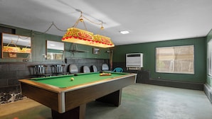 A pool table with chairs, a hanging light fixture, and a whiteboard in a room with green walls and a window. - Boulder Bay Lakefront Getaway (Big Bear Lake)