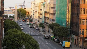 Uma rua urbana com edifícios, veículos e pedestres.
