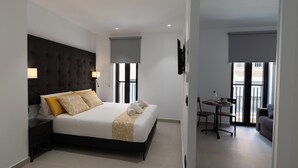 Quarto de hotel moderno com uma cama grande, uma escrivaninha e varanda com vista.