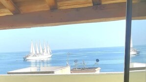 Vista de un yate grande en el agua, un muelle con un edificio, y un barco pequeño a lo lejos.