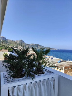 Een balkon met uitzicht op zee en een berg.