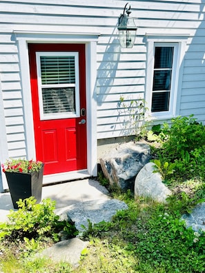 Stunning entrance with a red front door, black planter, and a lantern above a small window.