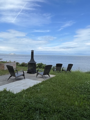 Relax in a serene outdoor space with a stove, four comfortable chairs, and a beautiful view.