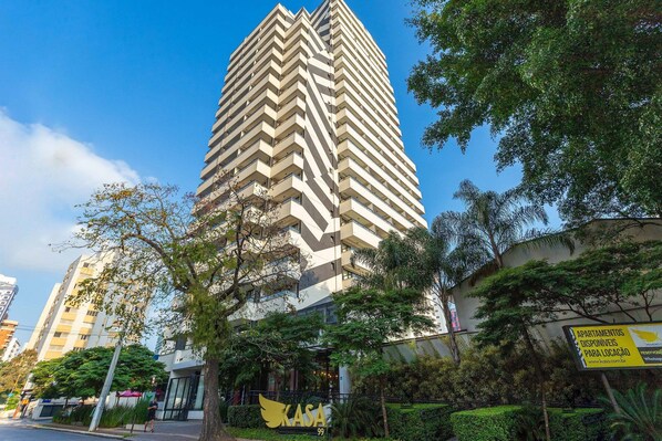 Un edificio alto y moderno con un diseño en zigzag, rodeado de árboles y follaje.