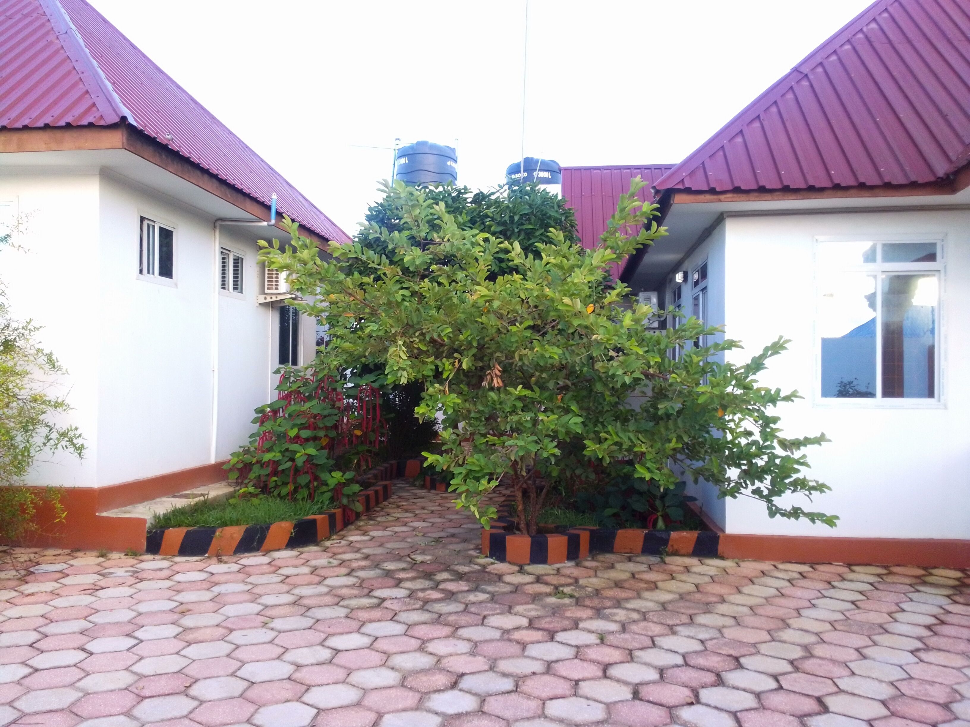 A courtyard with hexagonal tiled flooring, surrounded by buildings with red roofs and white walls.