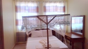 Una cama individual con estructura de madera y dosel, una mesita de noche y un espejo.