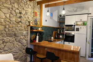 Een keuken met een stenen muur, een houten bar en moderne apparatuur.