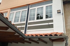 Ein Gebäude mit weißer Fassade, zahlreichen Fenstern und sichtbarer Dachkonstruktion.
