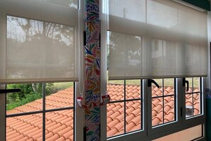 Ein Fenster mit Blick auf ein Ziegeldach und einem dekorativen Vorhang.