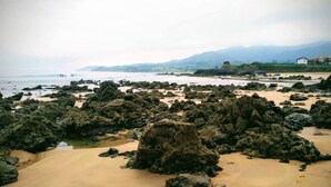 Ein felsiger Strand mit vereinzelten Felsen und einem sandigen Vordergrund.
