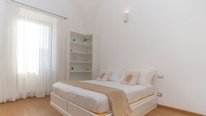 A bedroom with a bed, white curtains, a white shelving unit with plants, and a white wall. - La Casa di Sasà - Maiori - Amalfi Coast - Elegant Accomodation (Maiori)